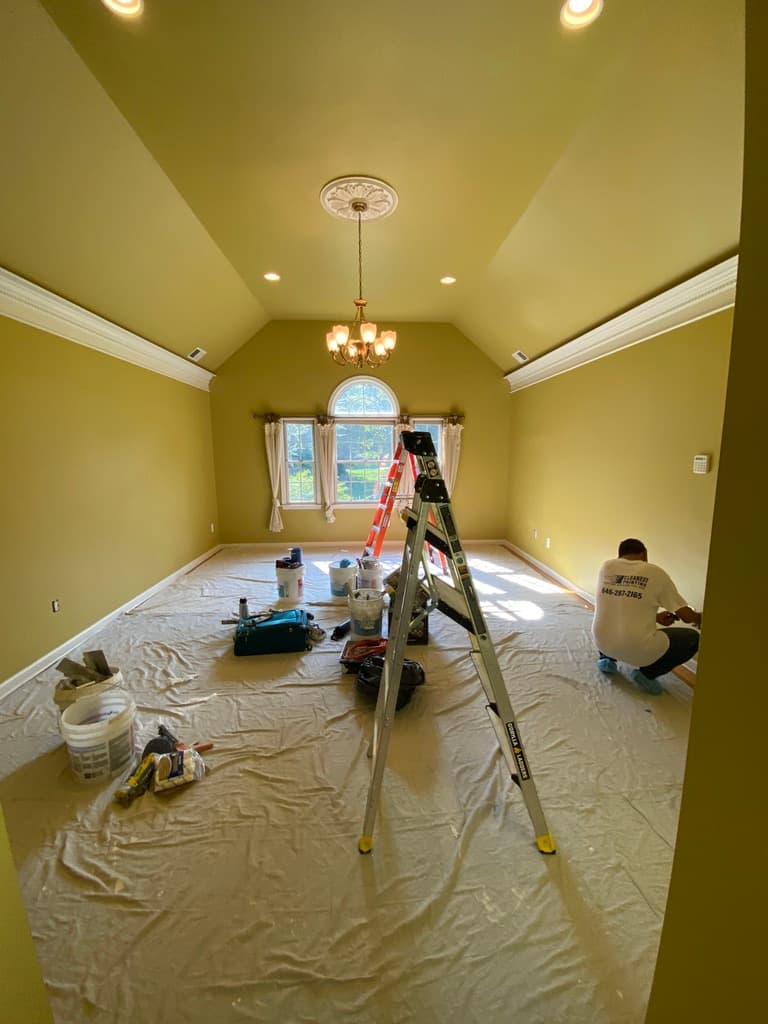 Interior painting of a vaulted ceiling living room with scaffolding and recessed lighting